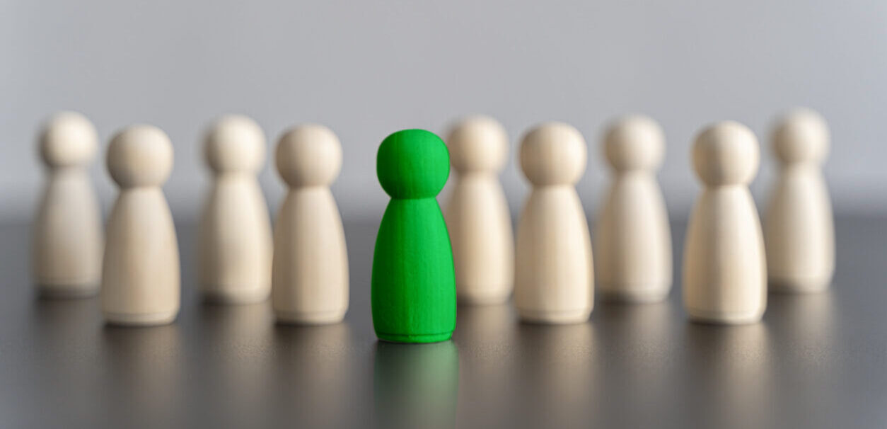 The green figure of a man comes out of the line of people. concept of success and improvement in work, the universal recognition of efficiency and leadership qualities. talent